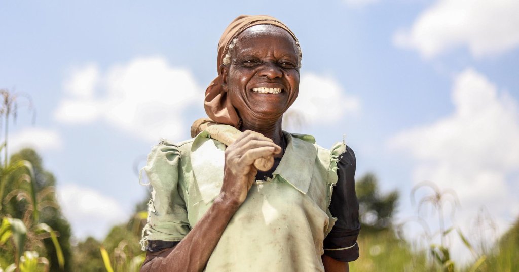 Die Bäuerin Melisa Khavala steht auf dem Feld und lächelt in die Kamera.